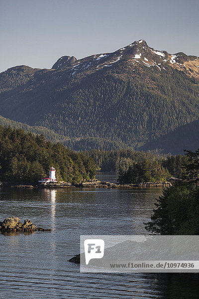 'Small islands populated by Sitka spruce trees  a lighthouse in the background; Sitka  Alaska  United States of America'