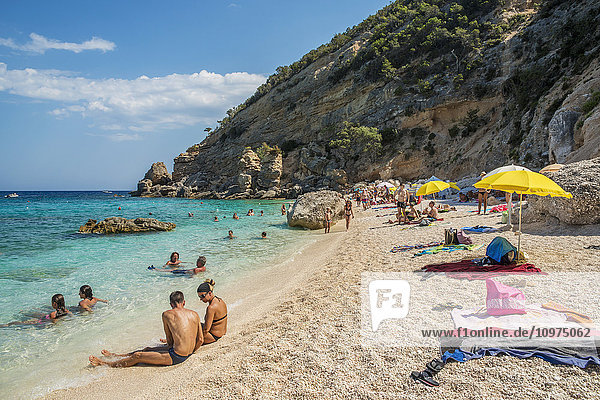 'Tourists swimming and sunbathing along the Mediterranean coast; Cala Gonone  Sardinia  Italy'