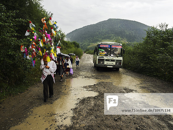 'Relatives and friends escort the bride to church on the road in the rain; Kryvorivnia  Verkhovyna district  Ivano-Frankivsk region  Ukraine.'