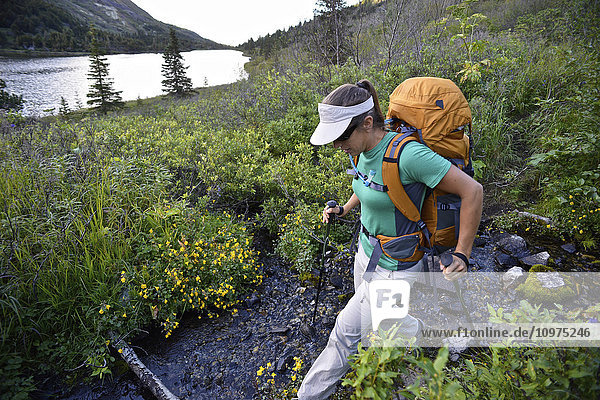 Woman backpacker hikes along Upper Fuller Lake in the Kenai National Wildlife Refuge on the Kenai Peninsula in South-central Alaska