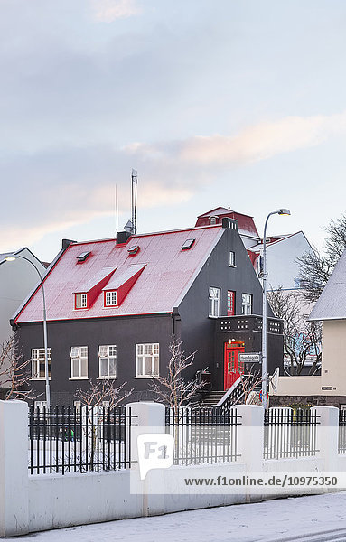 Ein braunes Gebäude mit rotem Dach in der Abenddämmerung im Winter; Reykjavik  Island'.