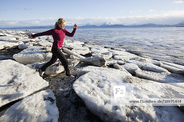 Woman running on the ice covered beach in Homer  Kenai Peninsula  Southcentral Alaska