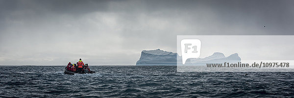 Aufblasbare Motoren steuern auf einen blauen Eisberg am Horizont zu; Antarktis .