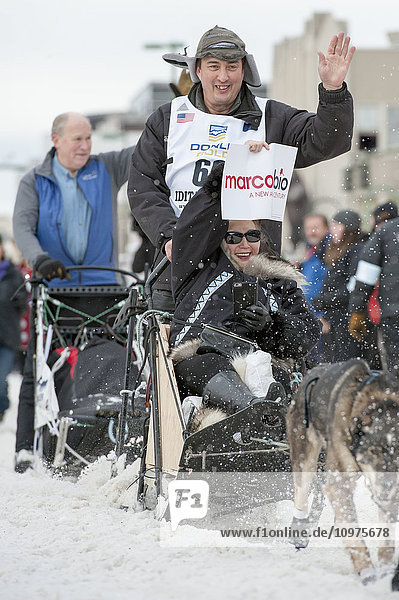 John Baker und sein Team verlassen die feierliche Startlinie mit einem Iditarider während des Iditarod 2016