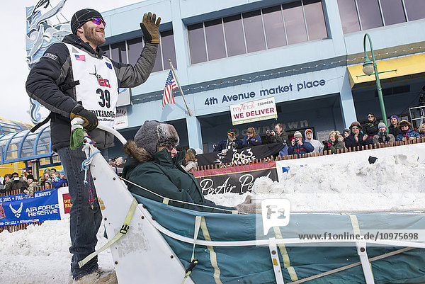 Noah Burmeister and team leave the ceremonial start line with an Iditarider during the 2016 Iditarod
