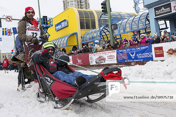 Lance Mackey and team leave the ceremonial start line with an Iditarider during the 2016 Iditarod