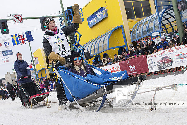 Zoya DeNure and team leave the ceremonial start line with an Iditarider during the 2016 Iditarod
