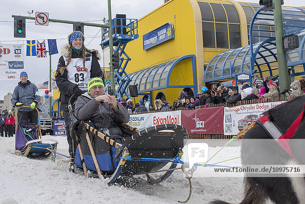 Kristy Berington and team leave the ceremonial start line with an Iditarider during the 2016 Iditarod