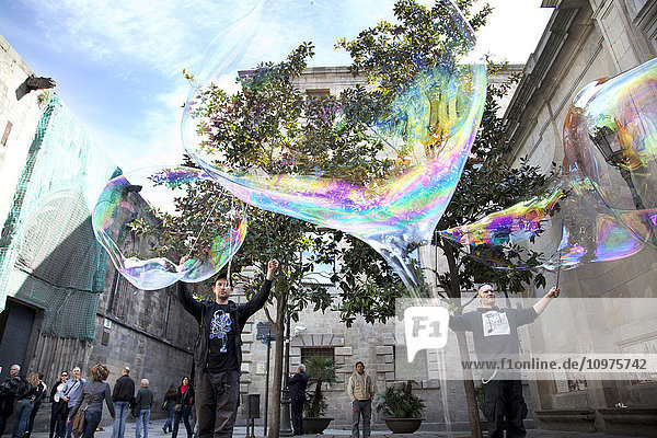 Männer mit großen Seifenblasen  die mit Stäben hergestellt wurden  auf dem Stadtplatz; Barcelona  Katalonien  Spanien