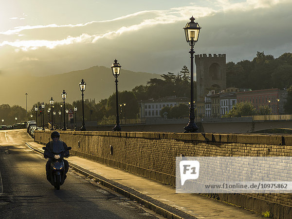 'Motorcyclist on a road leading over the Arno River; Florence  Toscana  Italy'