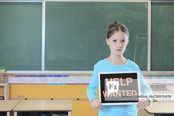 Junges Mädchen steht in einem Klassenzimmer und hält ein Schild Hilfe gesucht ; Toronto  Ontario  Kanada