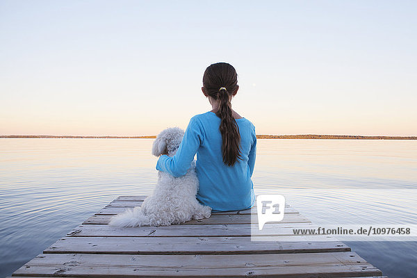 Mädchen sitzt mit ihrem Hund am Ende eines Stegs am Balsam Lake; Ontario  Kanada'.