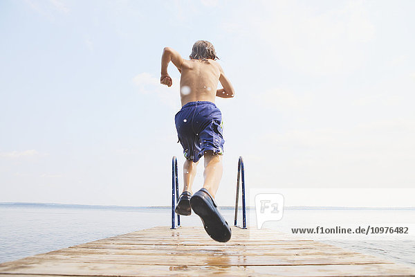 'Boy running to jump off end of dock on Balsam Lake; Ontario  Canada'