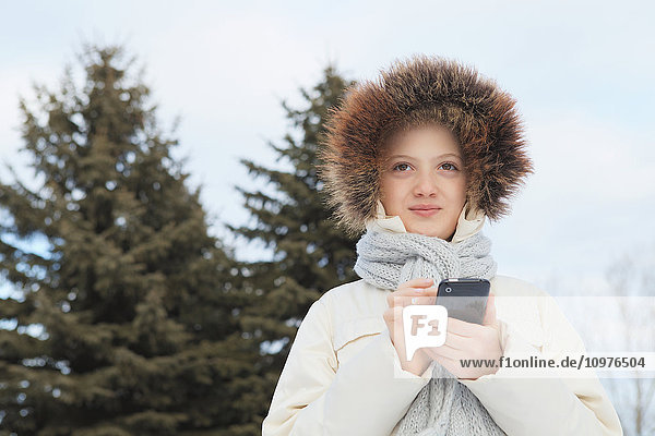Mädchen  das im Winter im Freien mit einem Smartphone telefoniert; Toronto  Ontario  Kanada'.