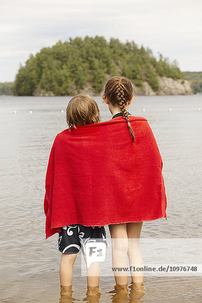 Bruder und Schwester  eingewickelt in ein Handtuch  stehen im Mara-See; Ontario  Kanada'.