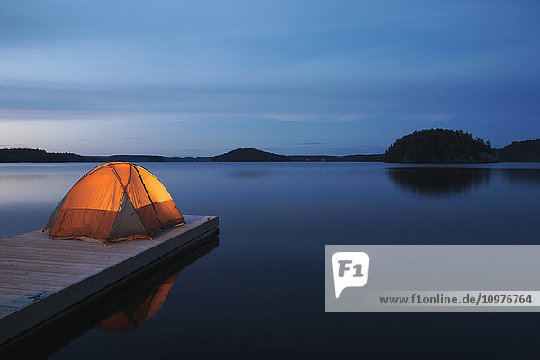 'Illuminated tent on dock at sunset on Mara Lake; Ontario  Canada'