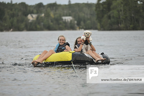'Girls with their pet dog being towed in a rubber raft; Lake of the Woods  Ontario  Canada'