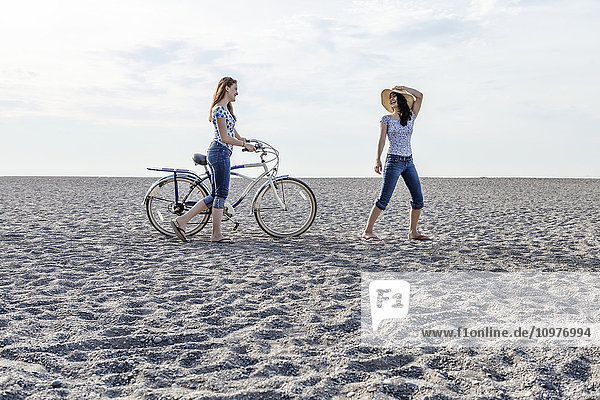 'Two girls walking on beach with bike; Toronto  Ontario  Canada'