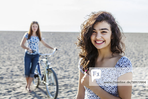 'Two girls standing on a beach with bike; Toronto  Ontario  Canada'