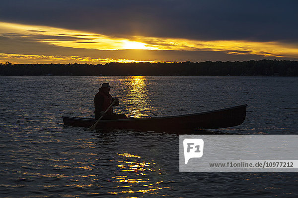 'Man paddling canoe at sunrise on Balsam Lake; Ontario  Canada'