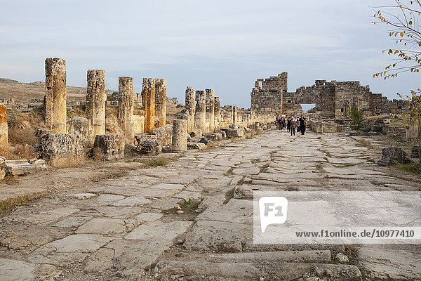 Tourist geht entlang der Ruinen einer antiken Straße; Pamukkale  Türkei'.