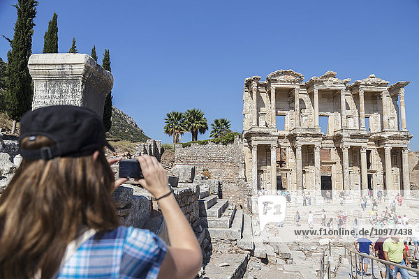 Eine Touristin fotografiert die Bibliothek des Celsus in den Ruinen von Ephesus; Ephesus  Izmir  Türkei'.