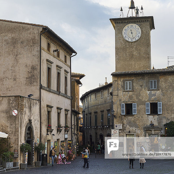 Uhrturm und Fußgänger vor einem Geschäft; Orvieto  Umbrien  Italien