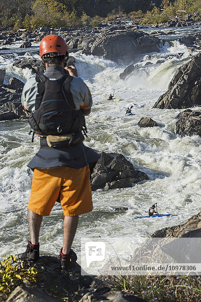 'Kayaker filming others whitewater kayaking rapids in the Potomac River  Great Falls Park; Maryland  United States of America'