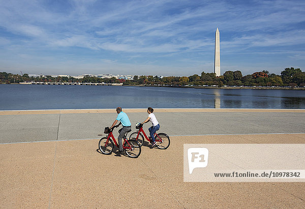 'Visitors riding bikeshare bikes along Tidal Basin directly in front of the Thomas Jefferson Memorial with the Washington Monument in the background; Washington  District of Columbia  United States of America'