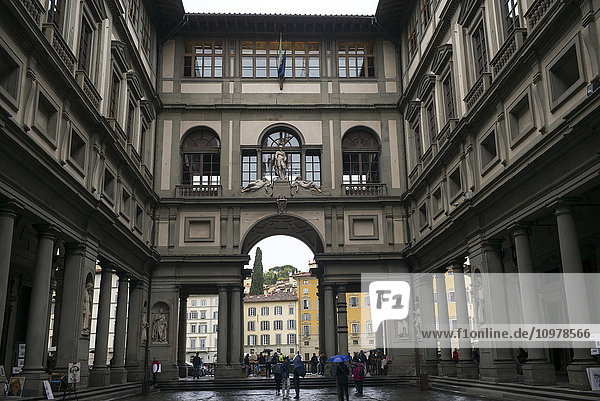 'Pedestrians walking in the courtyard of a building with columns; Florence  Italy'