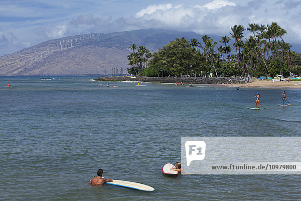 'Surfers  stand up paddlers  Cove Park Beach  West Maui Mountains in the distance; Kihei  Maui  Hawaii  United States of America'