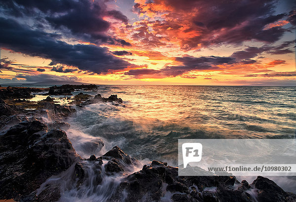 Dramatischer farbenfroher Himmel bei Sonnenuntergang über dem Pazifischen Ozean und der zerklüfteten Küstenlinie einer hawaiianischen Insel; Hawaii  Vereinigte Staaten von Amerika