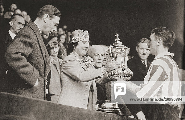 König George VI. und Königin Elizabeth überreichen Raich Carter  dem Kapitän von Sunderland  nach dem Sieg seiner Mannschaft in Wembley 1937 den Pokal. Aus The Sphere  Coronation Record Number  veröffentlicht 1937.