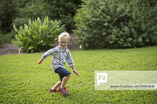 Ein fünfjähriger Junge rennt durch eine Wiese im JC Raulston Arboretum; Raleigh  North Carolina  USA'.
