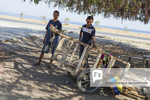 Männer und Mädchen an einem Schubkarren; Dili  Osttimor'.