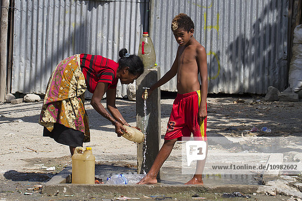 Frau und Junge an einer Wasserpumpe; Manatuto  Osttimor