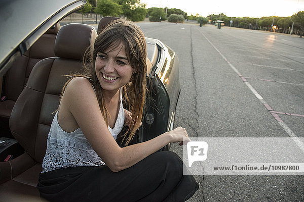 Smiling young woman sitting in convertible