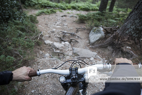 Mountainbiker fahren bergab auf felsigem Weg im Wald