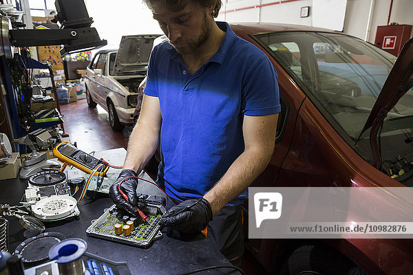 Mechaniker  der elektronische Autoteile in seiner Werkstatt repariert