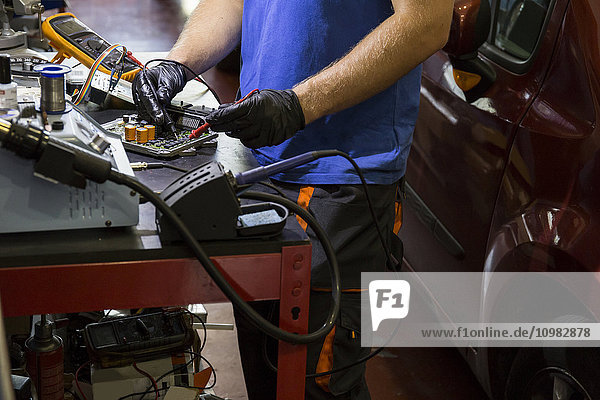 Mechanic fixing an electronic car parts in his workshop