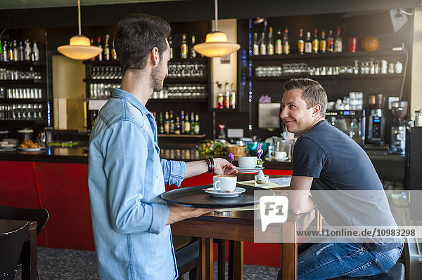 Kellner serviert Cappuccino im Cafe