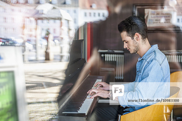 Junger Mann spielt Klavier in einem Cafe