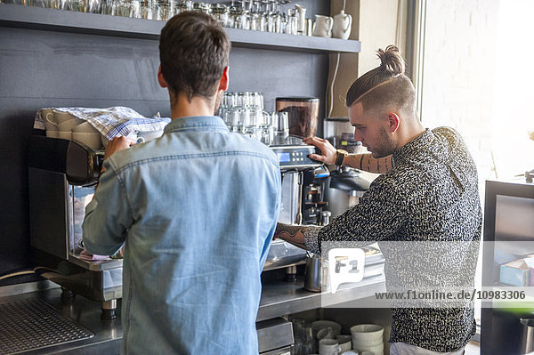 Zwei Männer bereiten Kaffee in einem Café zu.