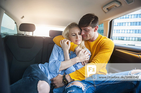 Verliebtes Paar kuschelt auf dem Rücksitz eines Autos