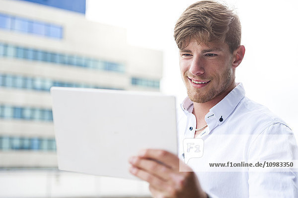 Junger Mann beim Betrachten des digitalen Tabletts im Freien