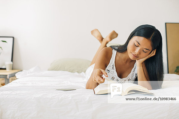 Junge Frau im Bett liegend Lesebuch