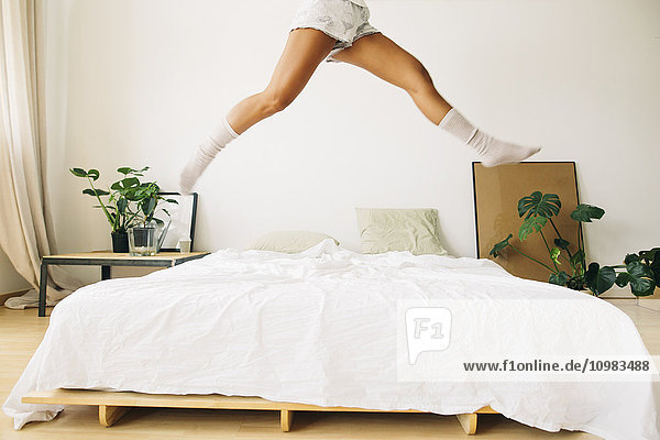 Beine einer jungen Frau  die auf dem Bett springt.