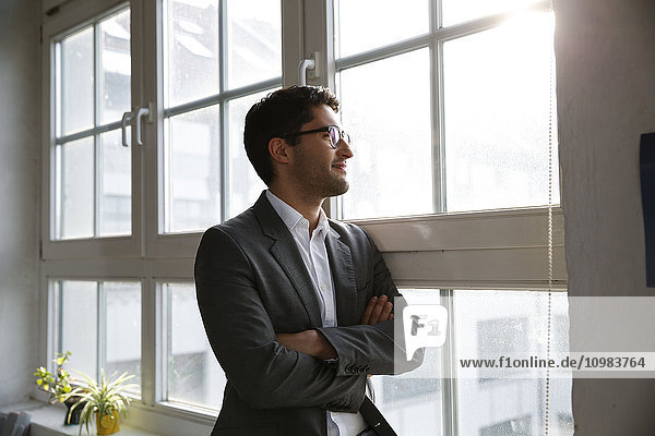 Businessman standing at the window with arms crossed