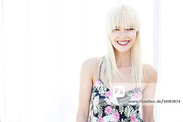 Porträt einer lächelnden blonden Frau vor hellem Hintergrund