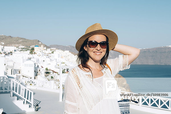 Griechenland  Santorini  Oia  Porträt der lächelnden Frau mit Sonnenbrille und Strohhut